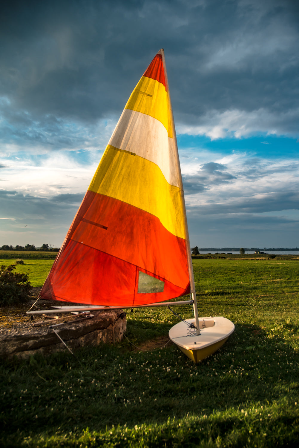 Bright sail extended against clouded skies on Wolfe Island, ON