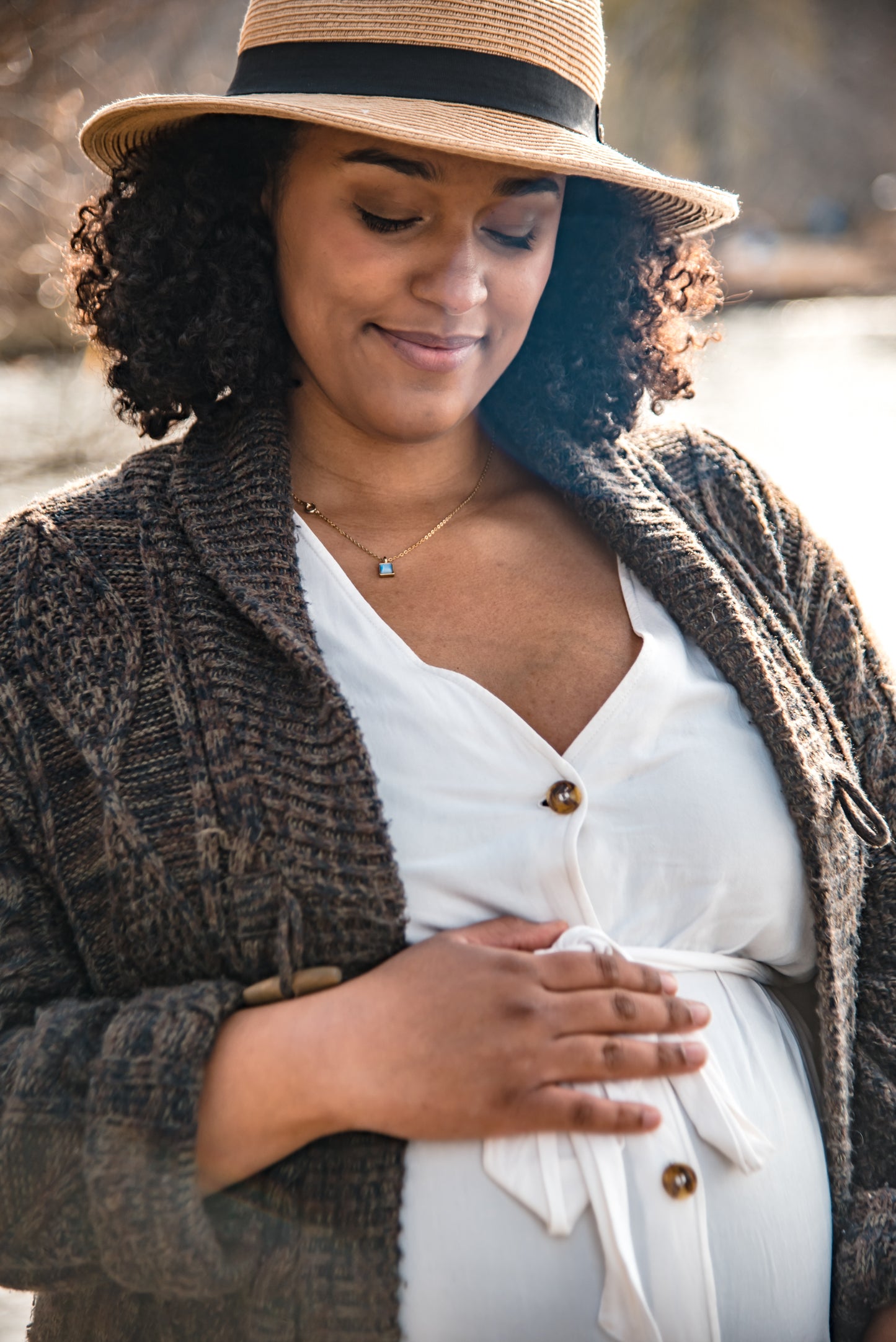 A young woman gently holds her pregnant belly, smiling at her unborn baby