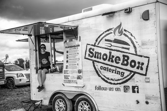 Woman sits in the window of the Smoke Box food truck at the MacKinnon Back to the Farm Beer Festival